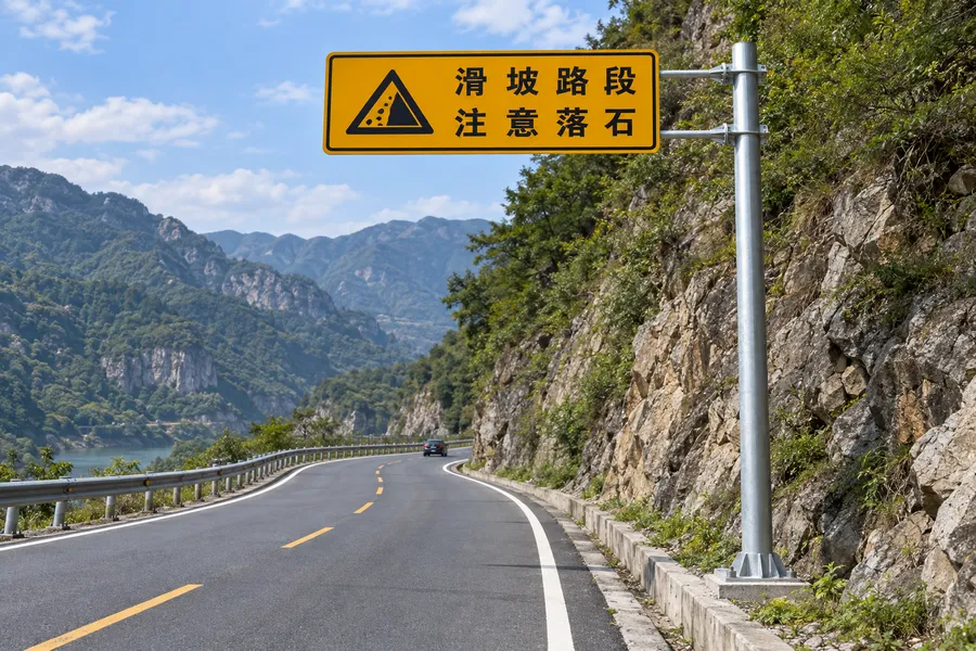山区公路旁支撑滑坡路段注意落石黄色警告牌的悬臂式标志杆