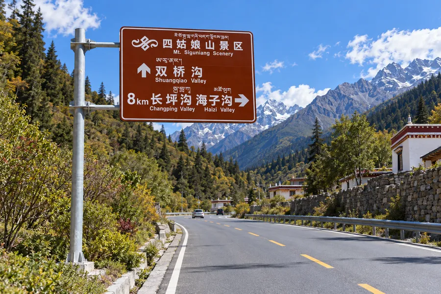 山区景区道路旁支撑棕色旅游导向牌的悬臂式标志杆